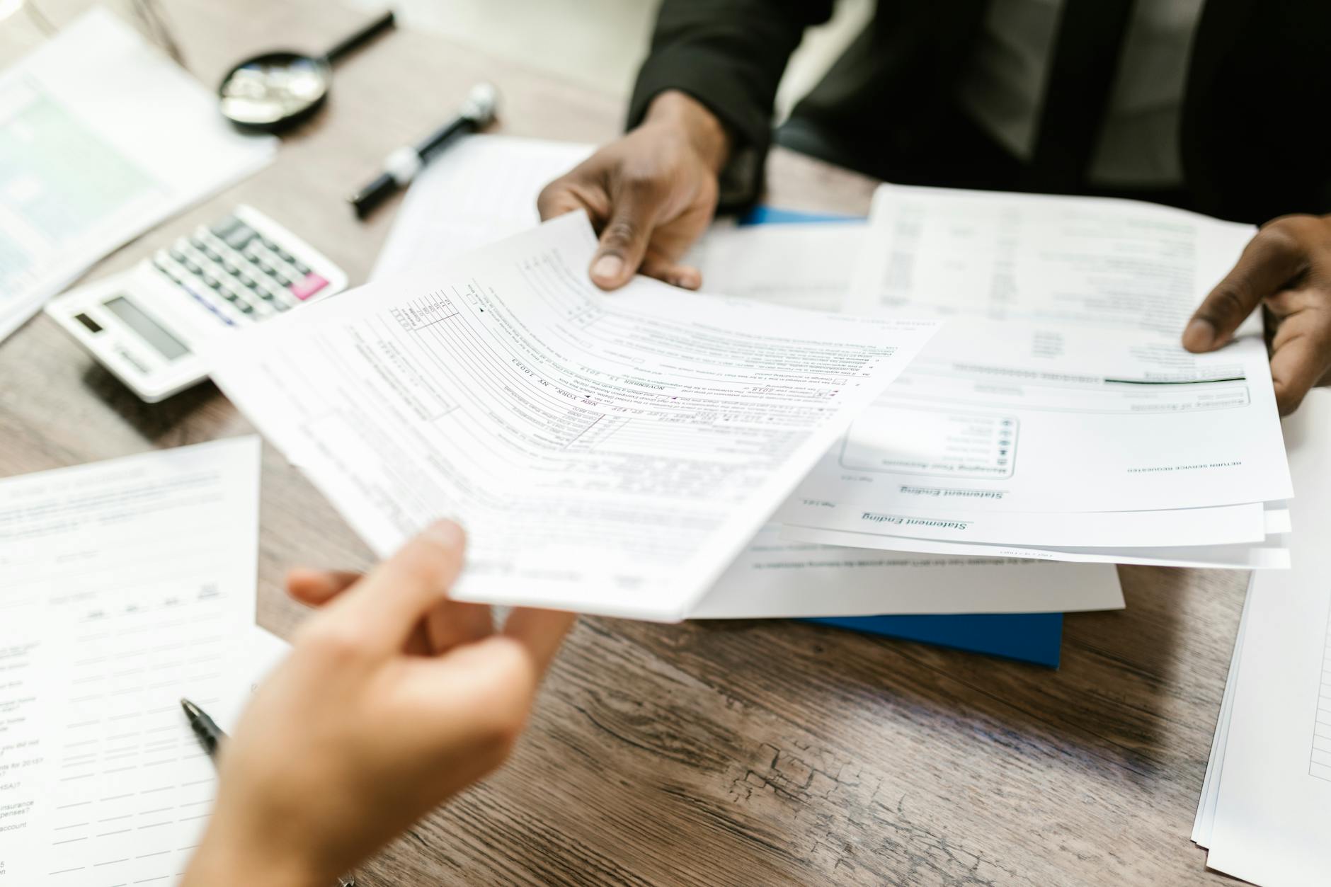 Decoratie photo of two hands exchanging documents across what looks like a desk.